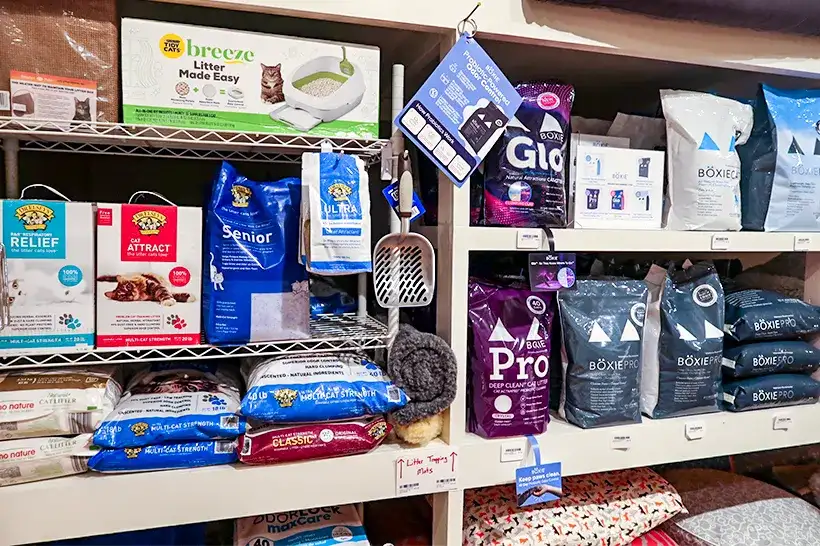 Shelves stocked with various brands of cat litter inside Tilley's Pet Supplies, a local pet store with affordable healthy cat food.