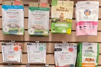 A shelf with various brands of natural supplements for cats inside Tilley's Pet Supplies, a pet store with grain free cat food .